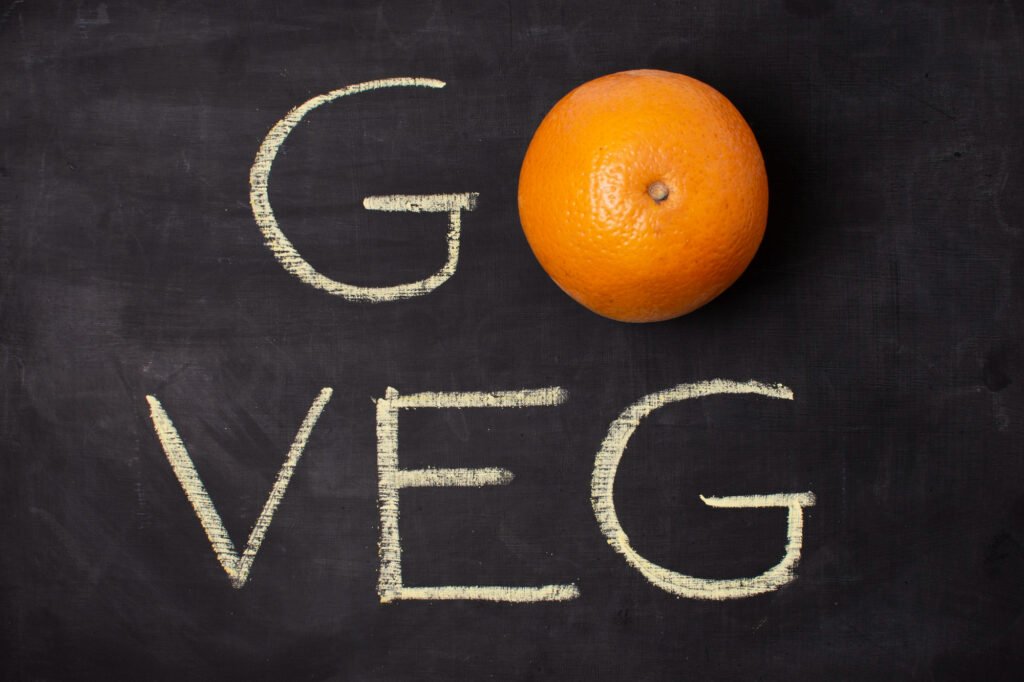 Une orange sur un tableau noir avec "Go Veg" inscrit à la craie, symbolisant une alternative à la consommation de viande.