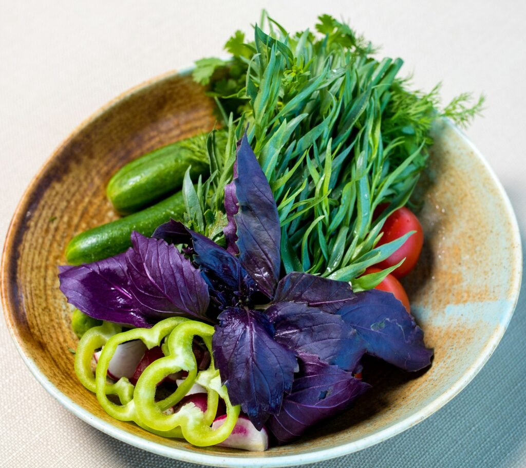 Bol de légumes verts et herbes fraîches, incontournables de l'alimentation végétalienne.