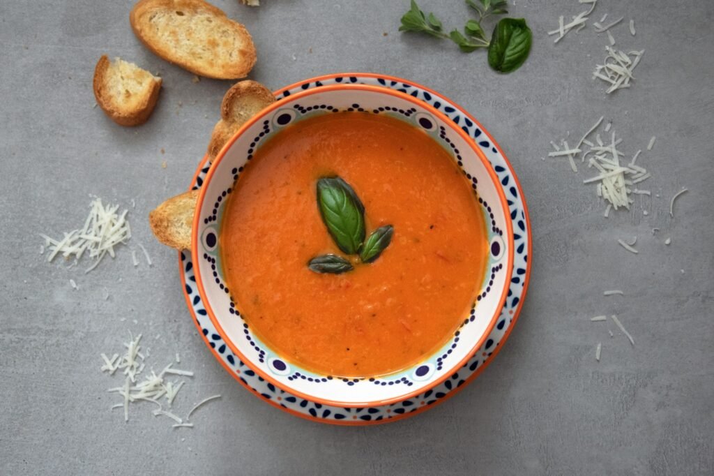 Bol de soupe tomate agrémenté de basilic et de pain grillé.