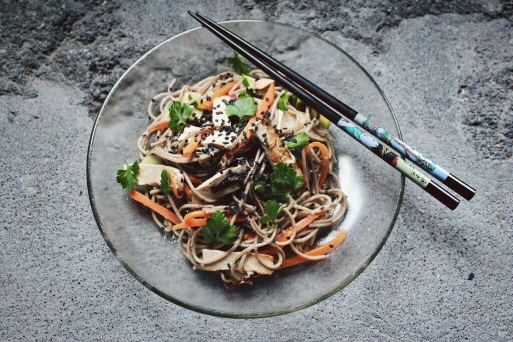Assiette de nouilles soba garnie de légumes, tofu grillé et sésame.