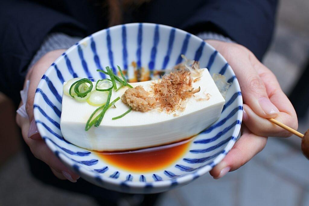 Bloc de tofu frais servi avec sauce miso, oignons verts et copeaux séchés.